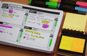 An open planner with items written, some highlighted in pink or yellow, is on a table with sticky notes and highlighters next to it.