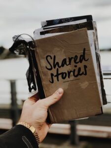 A handmade book with a brown cover and a few pictures hanging out and "Shared Stories" written on the front.