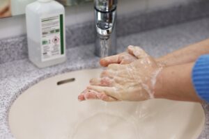 Hands being washed with soap under a faucet.