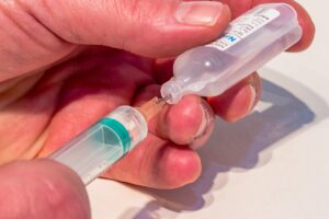 hands filling a syringe with medicine