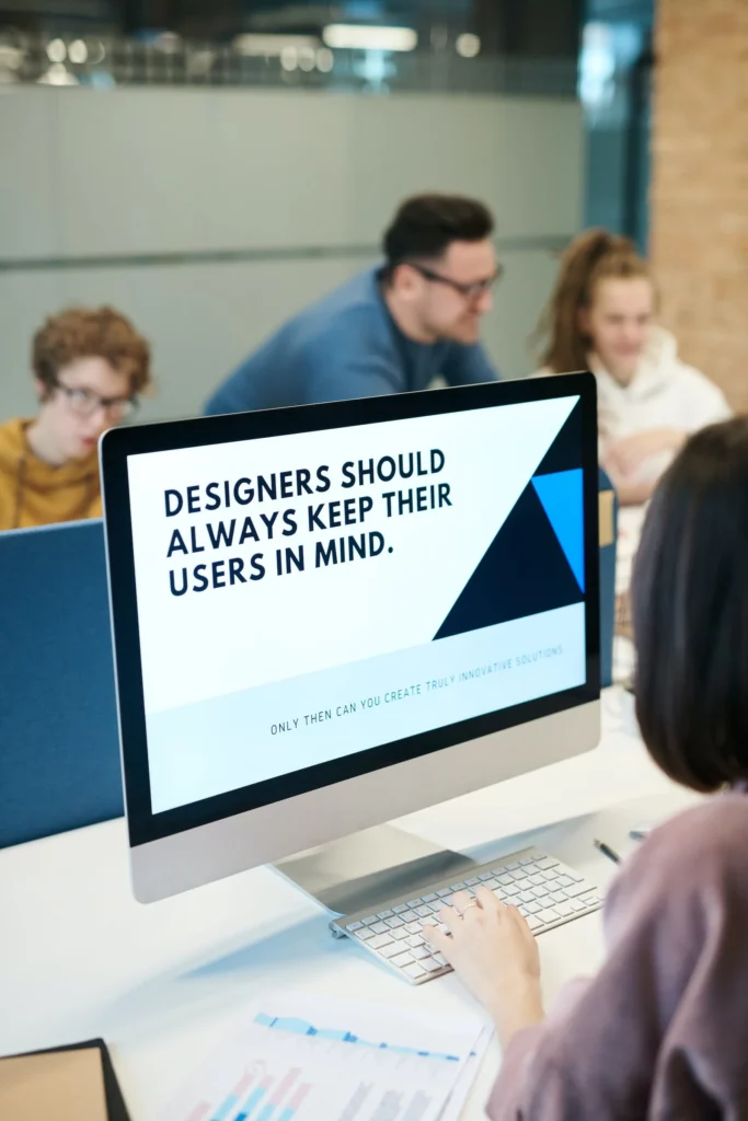 Person looking at computer monitor that reads, "Designers Should Always Keep Their Users in Mind." There are three people in the background.