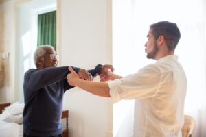 Young man helping older man with exercises