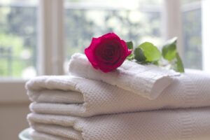 Pile of plush white towels with red rose on top