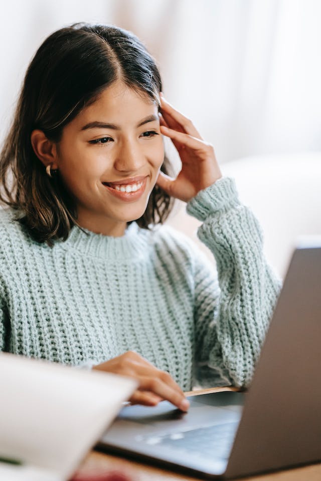 Smiling young woman working on laptop.