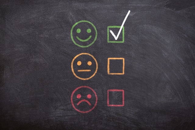 A blackboard shows a checkbox next to each: a frowning face in red, a non-expressive face in yellow, and a smiling face in green. There is a white checkmark by the smiling face.