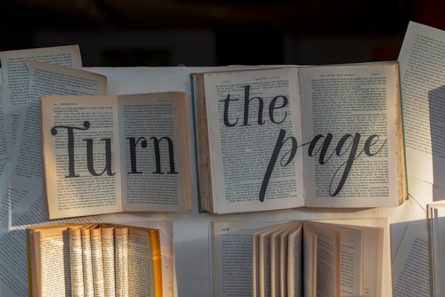 Several books open on a table. The phrase "Turn the page" is layered on top of them.