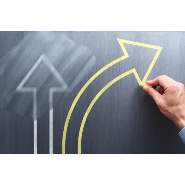 Person drawing new arrow on a blackboard, next to a partially-erased arrow going a different direction.