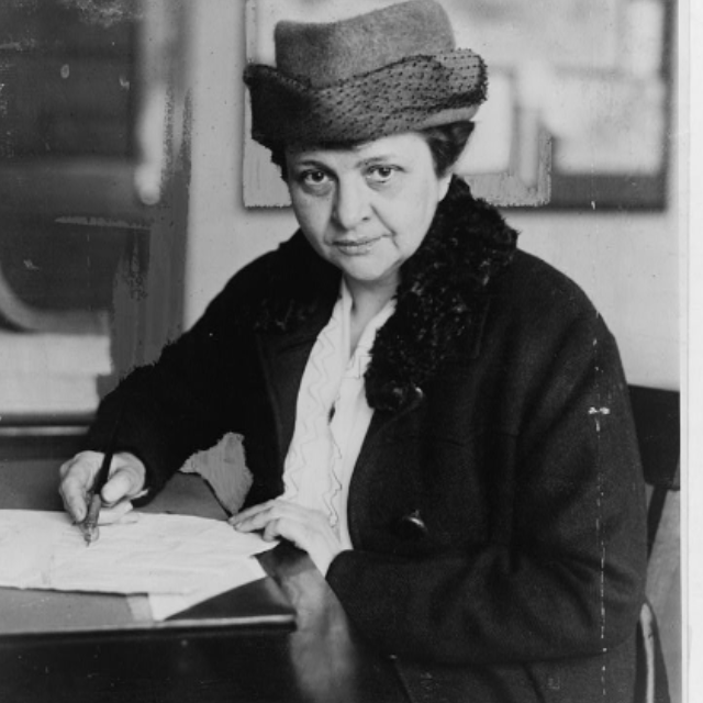 1918 photo of Perkins sitting at a desk while writing on a document.