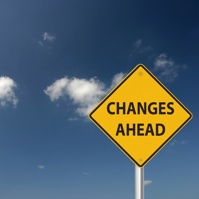 "Changes Ahead" on a yellow road sign against a blue sky background.