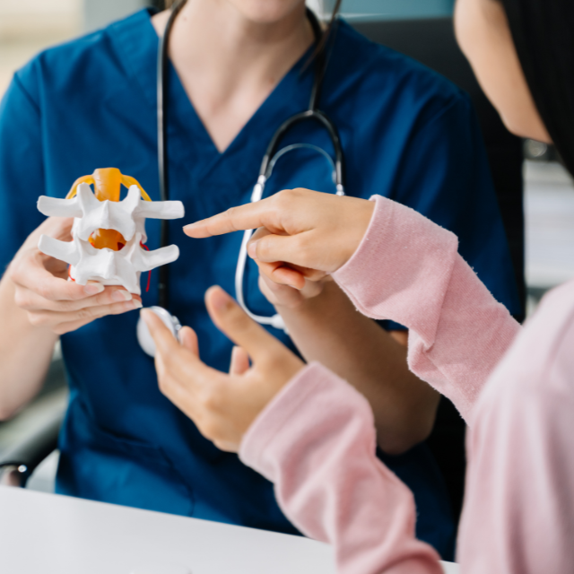 Person wearing blue scrubs and a stethoscope around their neck showing a splint to another person.