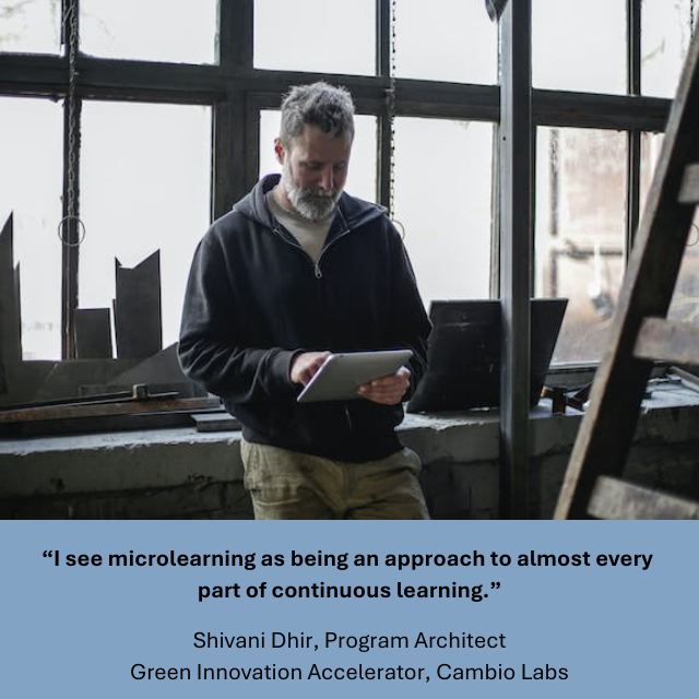 : A man with gray hair and a beard stands indoors by large industrial-style windows, looking down at and using a tablet. The setting appears to be a workshop or studio with natural light streaming in. Caption reads: “I see microlearning as being an approach to almost every part of continuous learning.” -Shivani Dhir, Program Architect, Green Innovation Accelerator, Cambia Labs